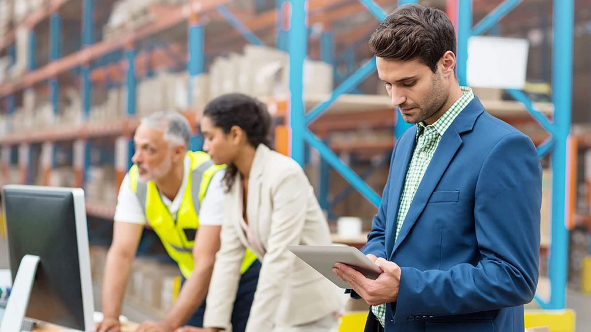 Trois personnes dans un entrepôt avec tablette et portable